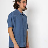 Man wearing a blue short-sleeve shirt against a white background
