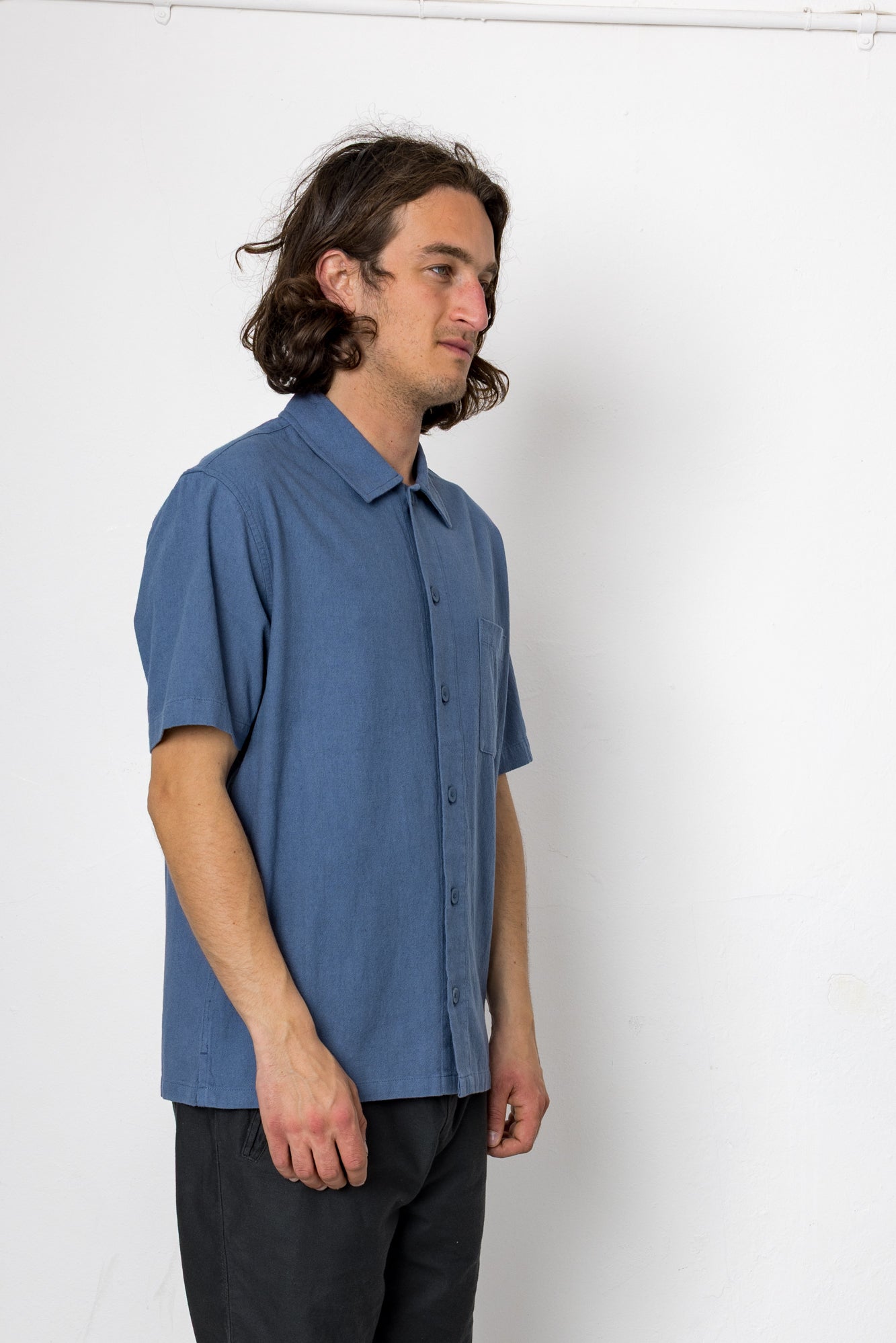 Man wearing a blue short-sleeve shirt against a white background