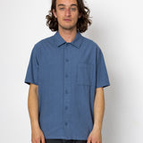 Man wearing a blue short-sleeve shirt against a white background