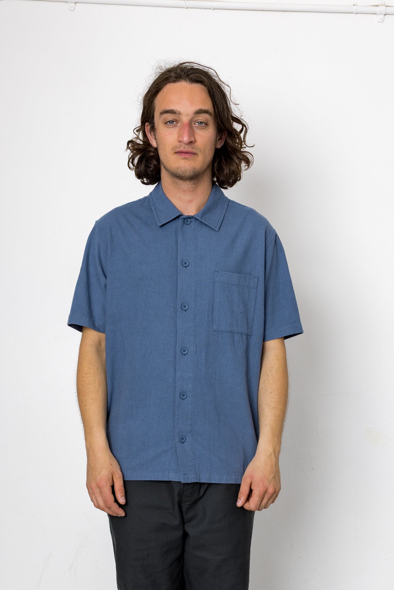Man wearing a blue short-sleeve shirt against a white background