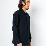 Man wearing a black shirt and gray pants against a white background