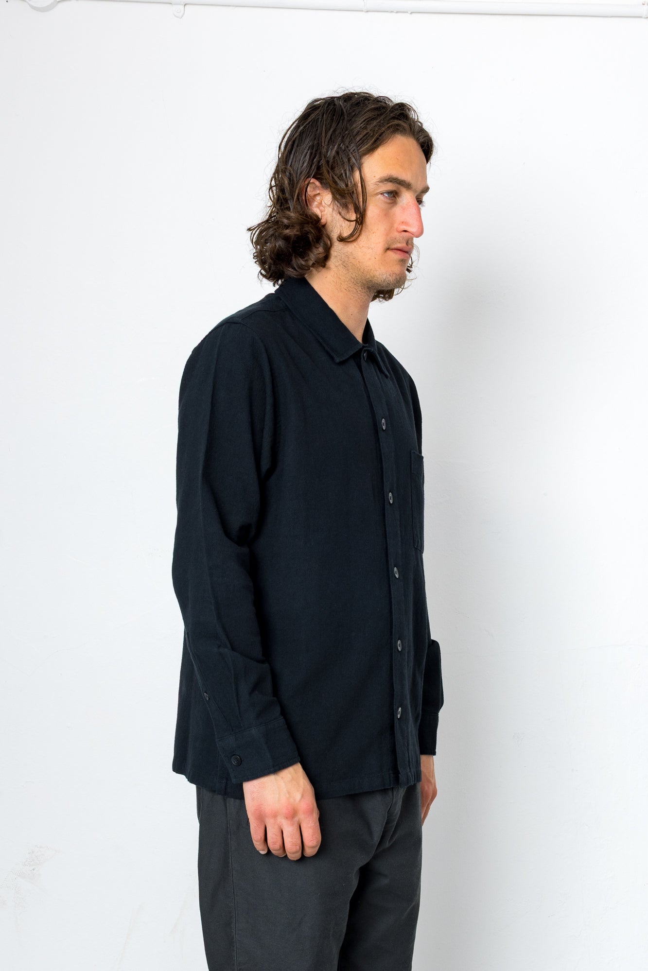 Man wearing a black shirt and gray pants against a white background