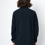 Person wearing a black shirt and dark pants against a white background