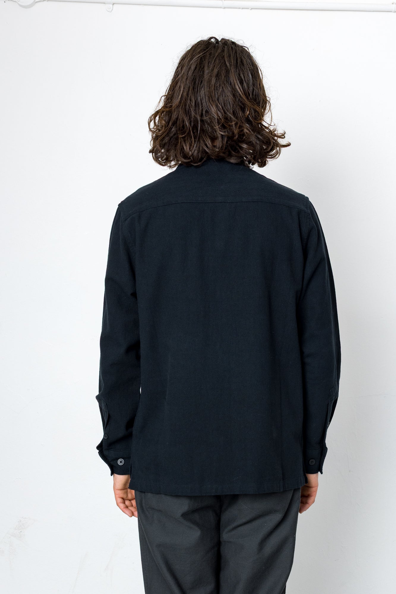 Person wearing a black shirt and dark pants against a white background