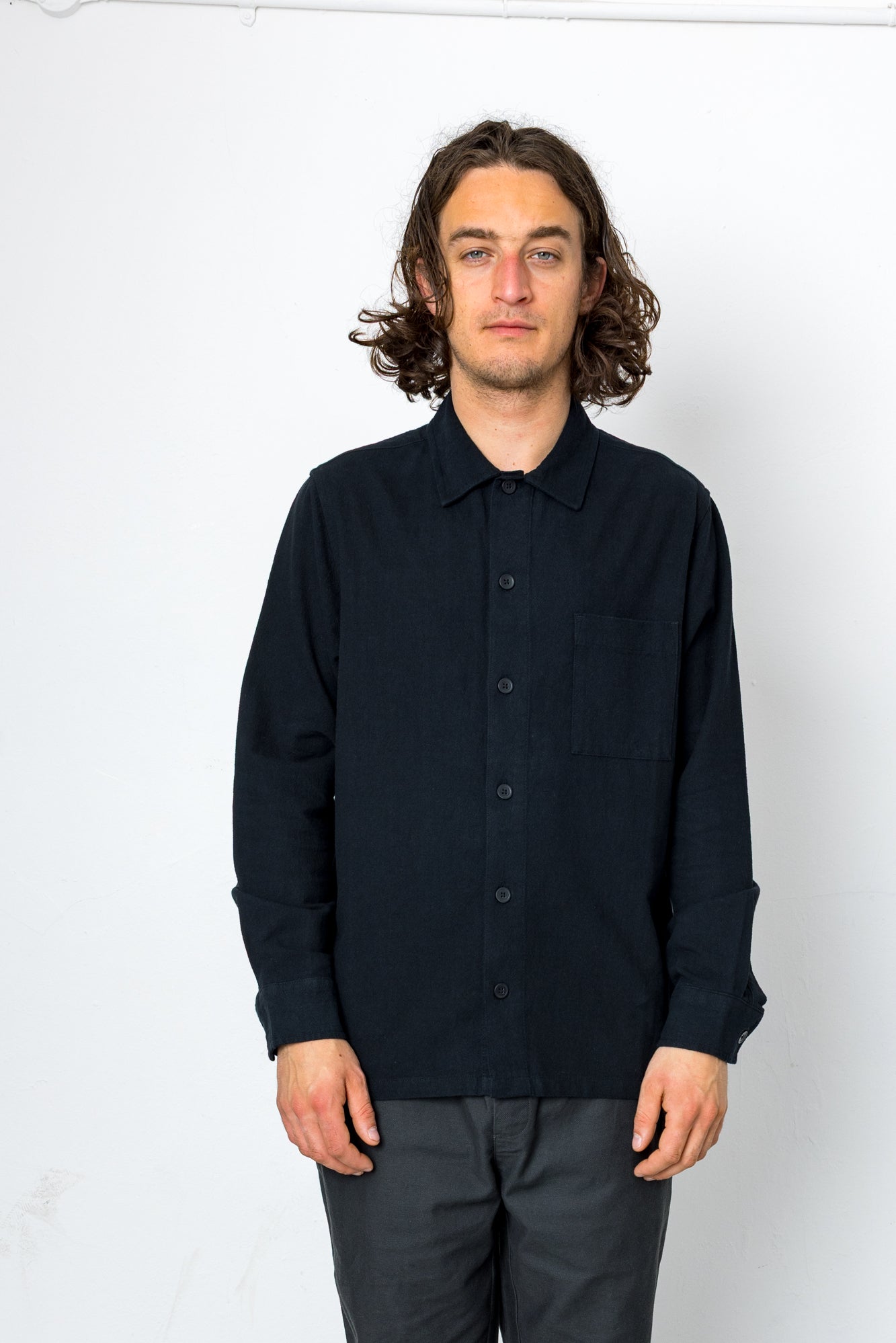 Man wearing a black button-up shirt against a white background