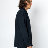 Man wearing a dark jacket and pants against a white background
