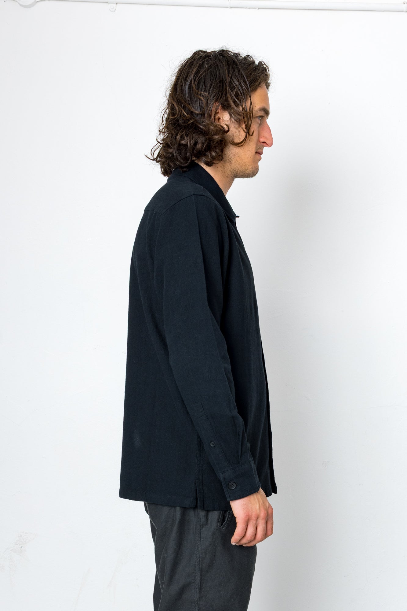 Man wearing a dark jacket and pants against a white background