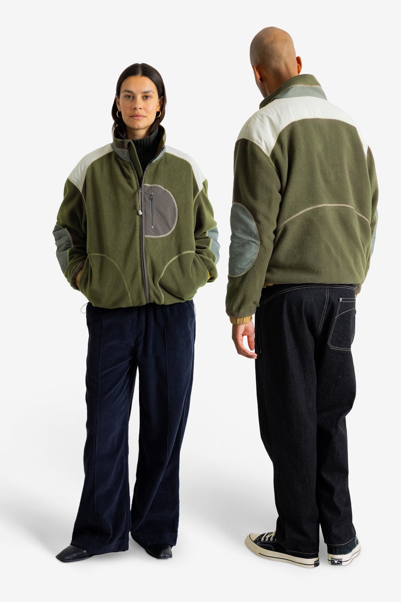 A man and a woman modeling an olive green fleece jacket with contrasting white shoulder panels, gray elbow patches, and a gray zippered chest pocket, shown from both front and back views against a plain white studio background.