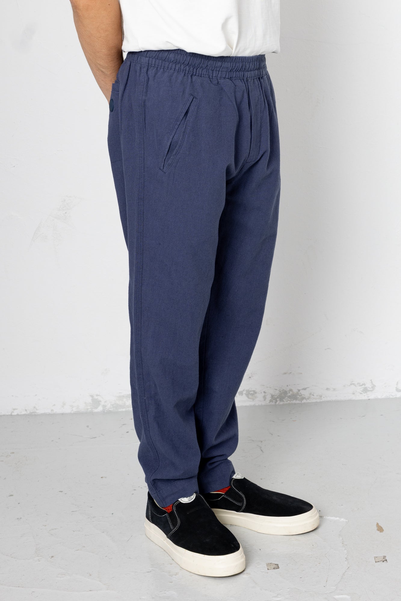 Person wearing blue pants and black shoes on a white background
