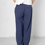 Person wearing blue pants and a white shirt against a plain background