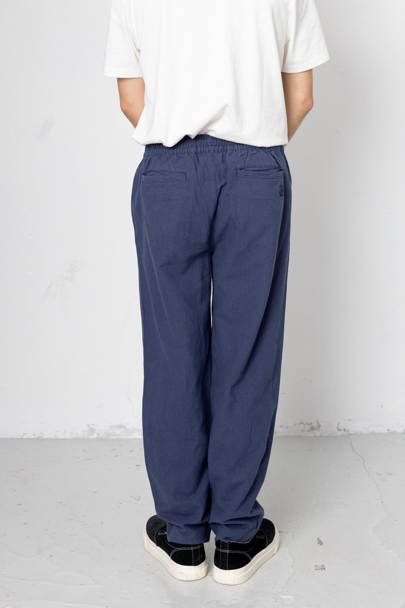 Person wearing blue pants and a white shirt against a plain background