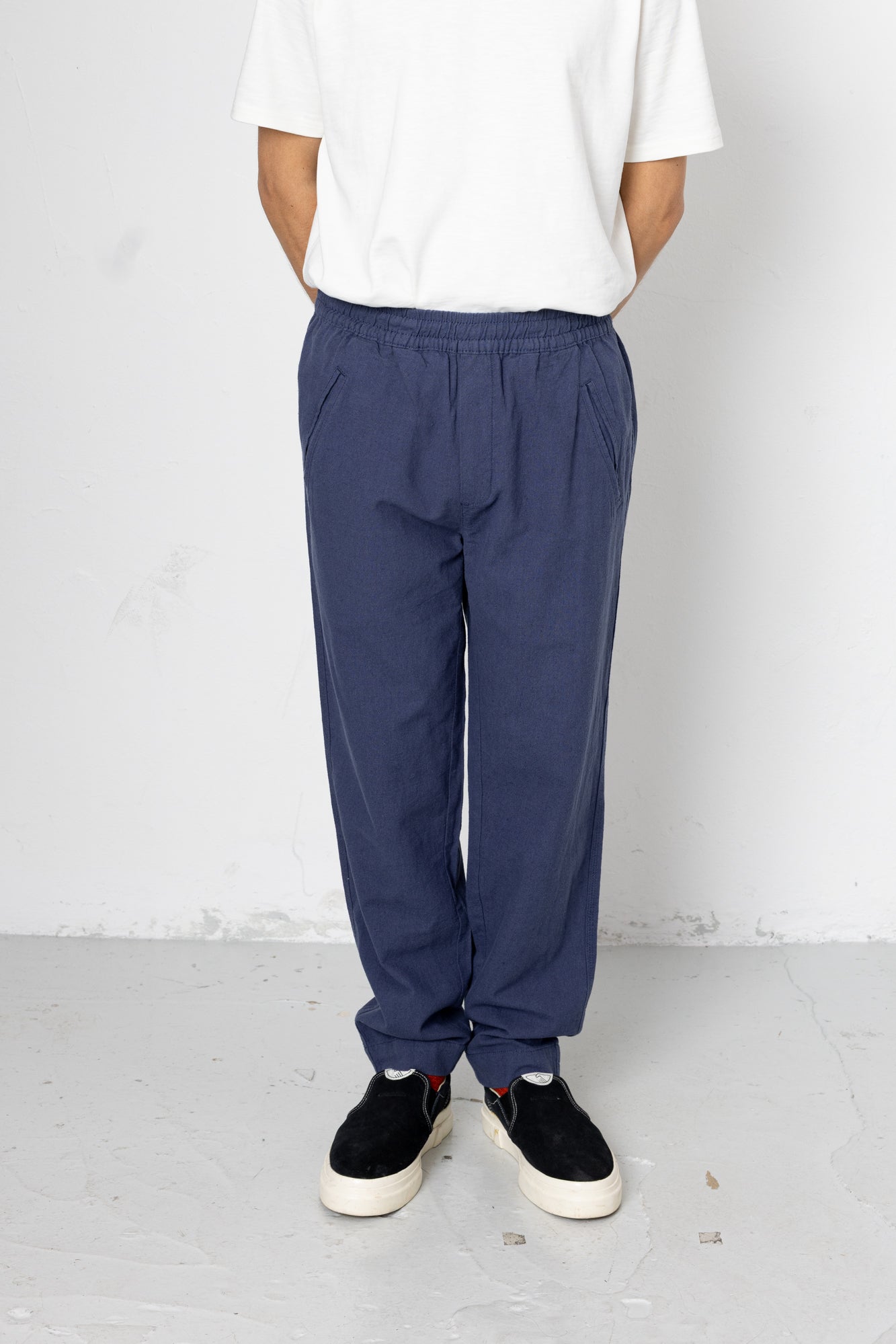 Person wearing blue pants and a white shirt against a plain background
