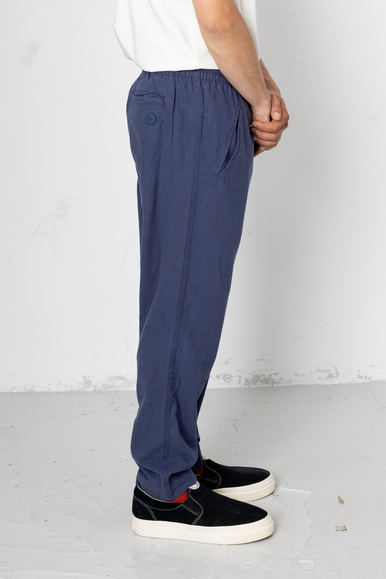 Person wearing blue pants and black shoes on a white background