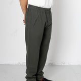 Person wearing dark gray pants and black shoes on a white background
