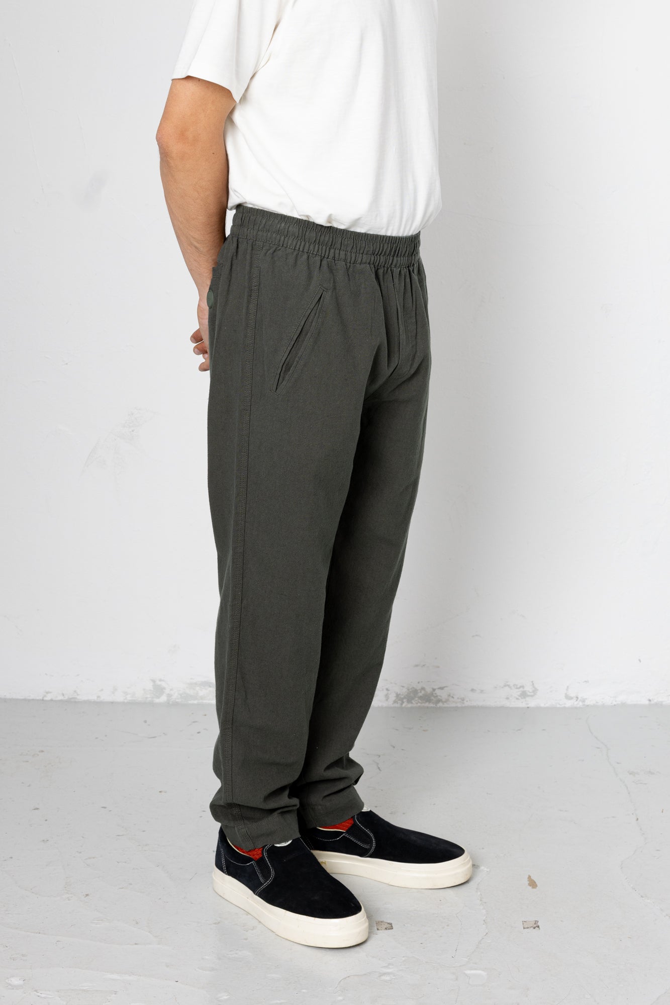 Person wearing dark gray pants and black shoes on a white background
