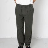 Person wearing dark gray pants and black shoes on a white background
