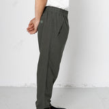 Person wearing dark gray pants and black sneakers on a white background