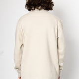 Person wearing a beige sweater with a plain white background