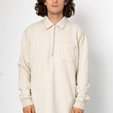Man wearing a beige long-sleeve shirt with a collar on a white background