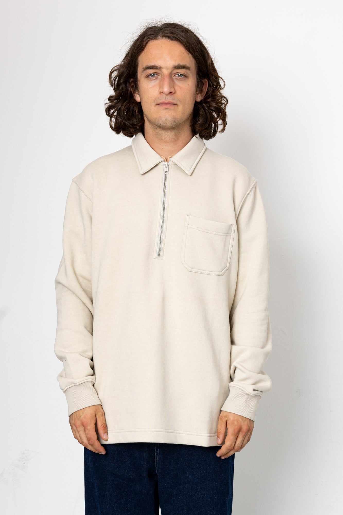 Man wearing a beige long-sleeve shirt with a collar on a white background