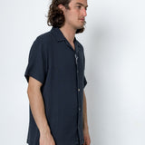 Man wearing a dark blue textured shirt against a white background