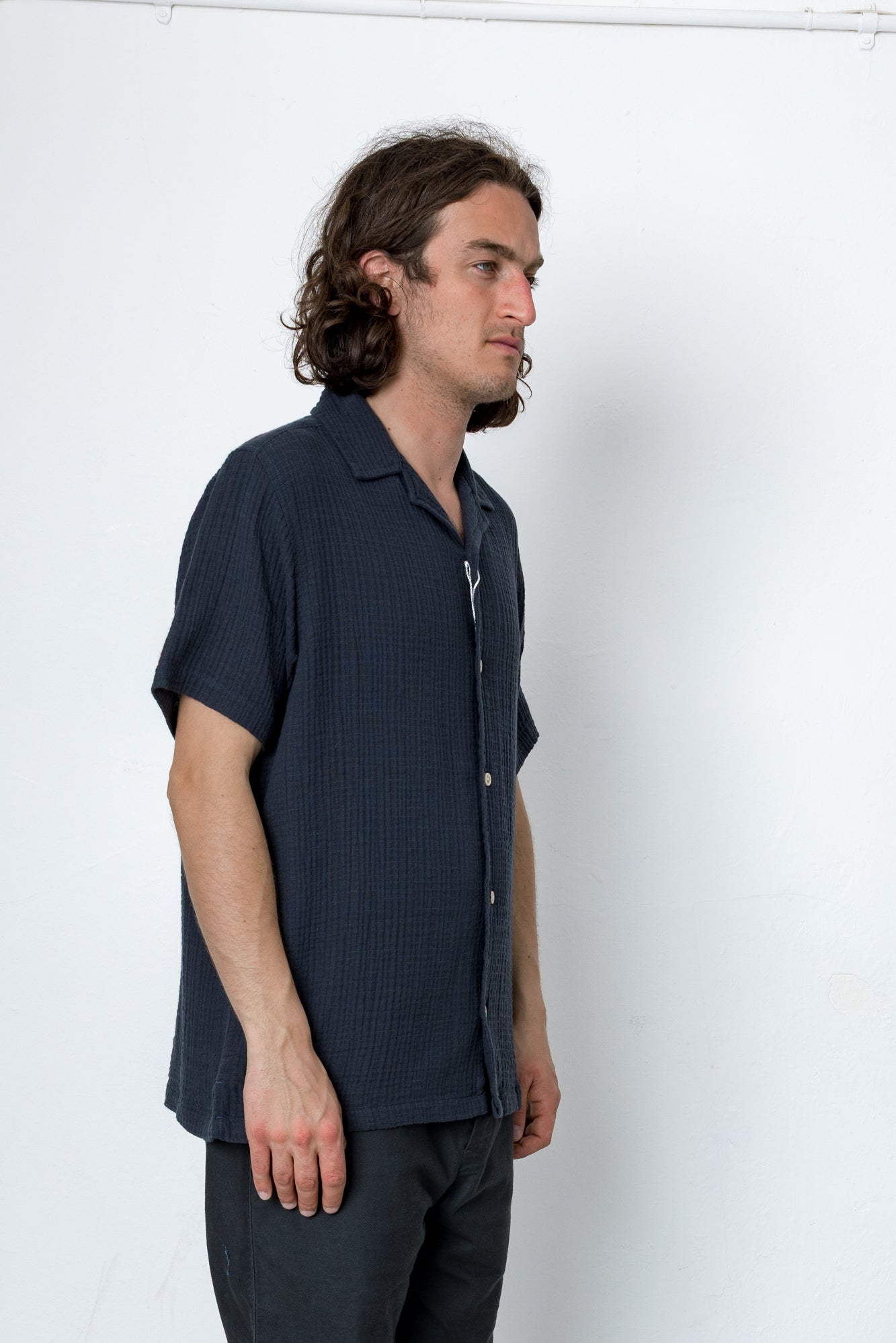 Man wearing a dark blue textured shirt against a white background