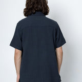 Person wearing a dark blue shirt and pants against a white background