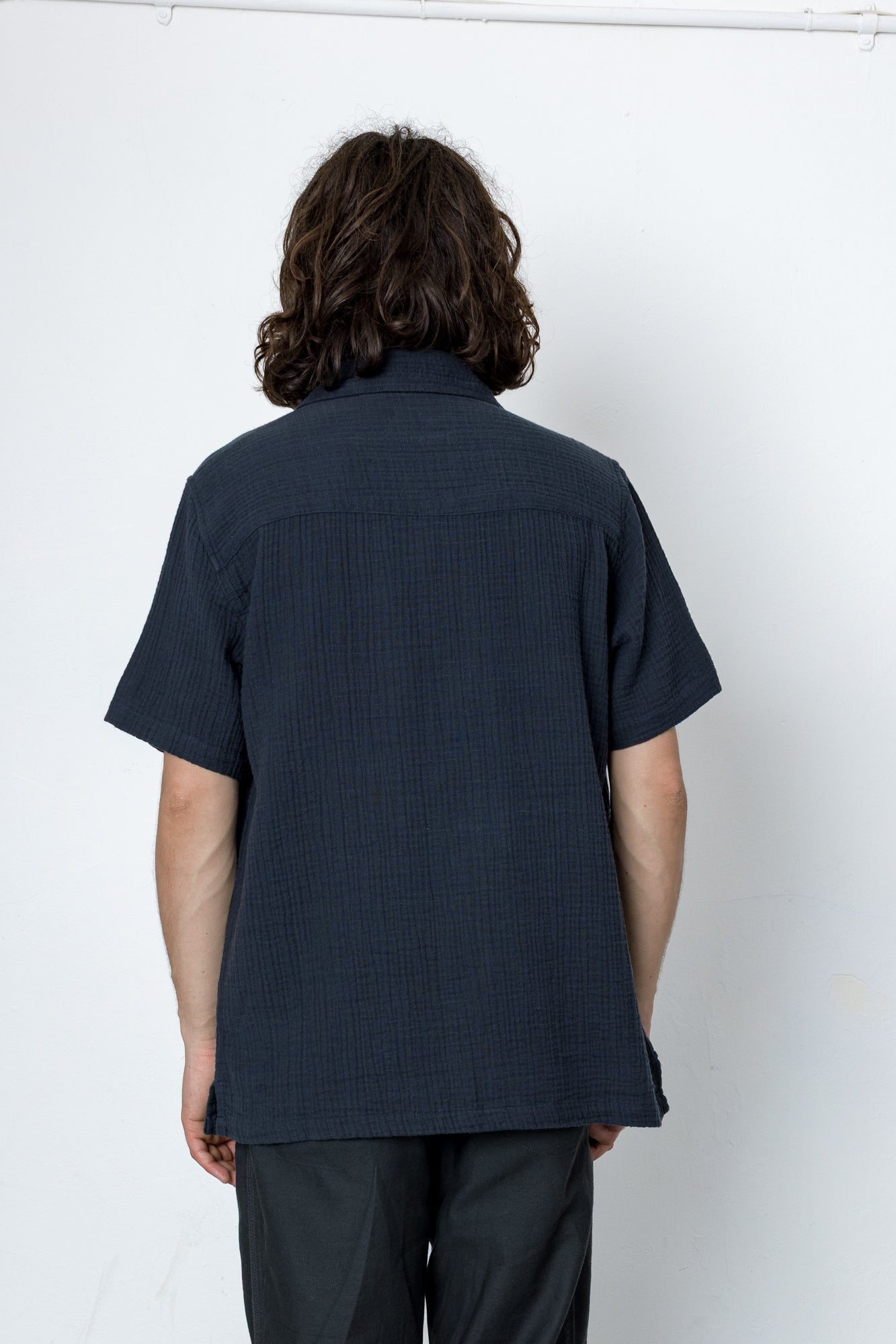 Person wearing a dark blue shirt and pants against a white background
