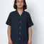 Man wearing a dark blue short-sleeve shirt with buttons against a white background