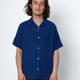 Man wearing a blue short-sleeve shirt against a white background