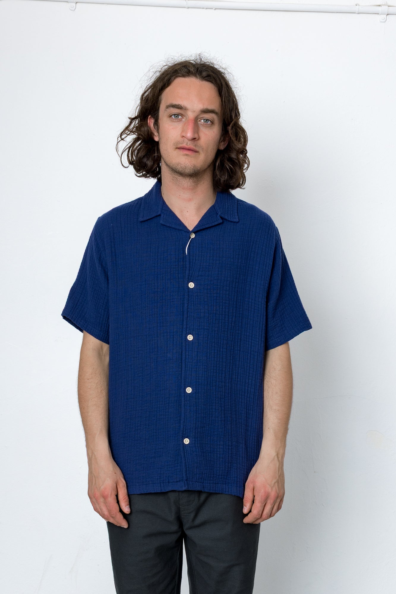 Man wearing a blue short-sleeve shirt against a white background