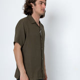 Man wearing a brown short-sleeve shirt against a white background