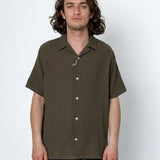 Man wearing a brown short-sleeve shirt against a white background