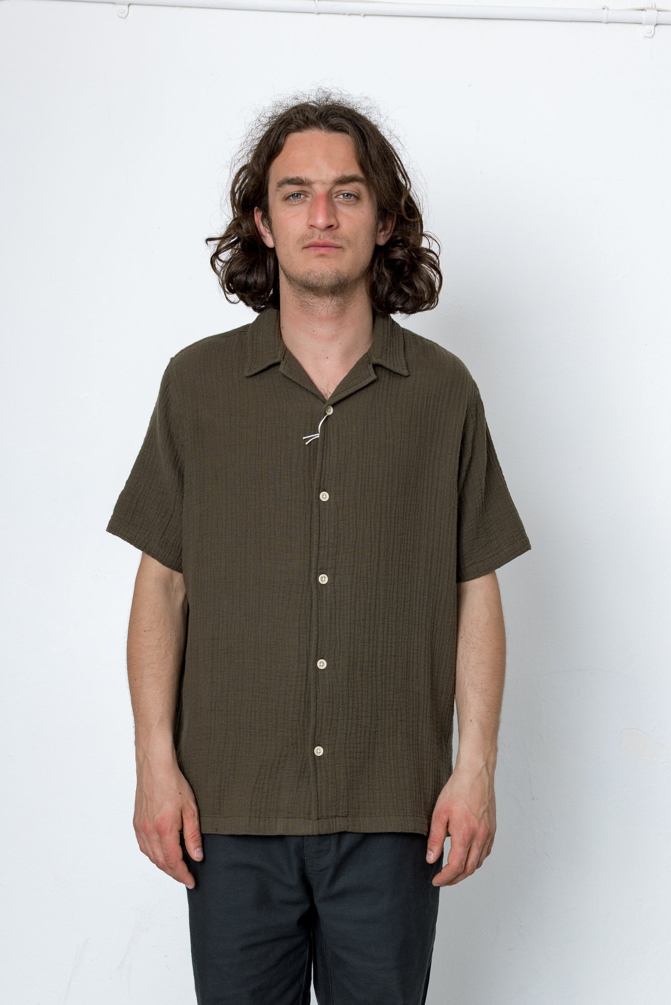 Man wearing a brown short-sleeve shirt against a white background