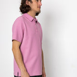 Person wearing a pink polo shirt against a white background