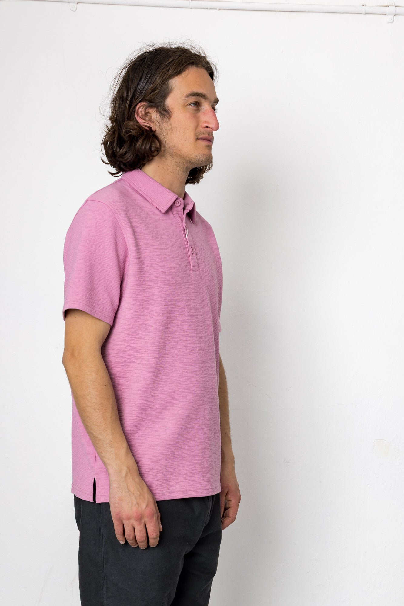 Person wearing a pink polo shirt against a white background