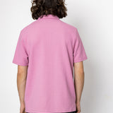 Person wearing a pink polo shirt against a white background