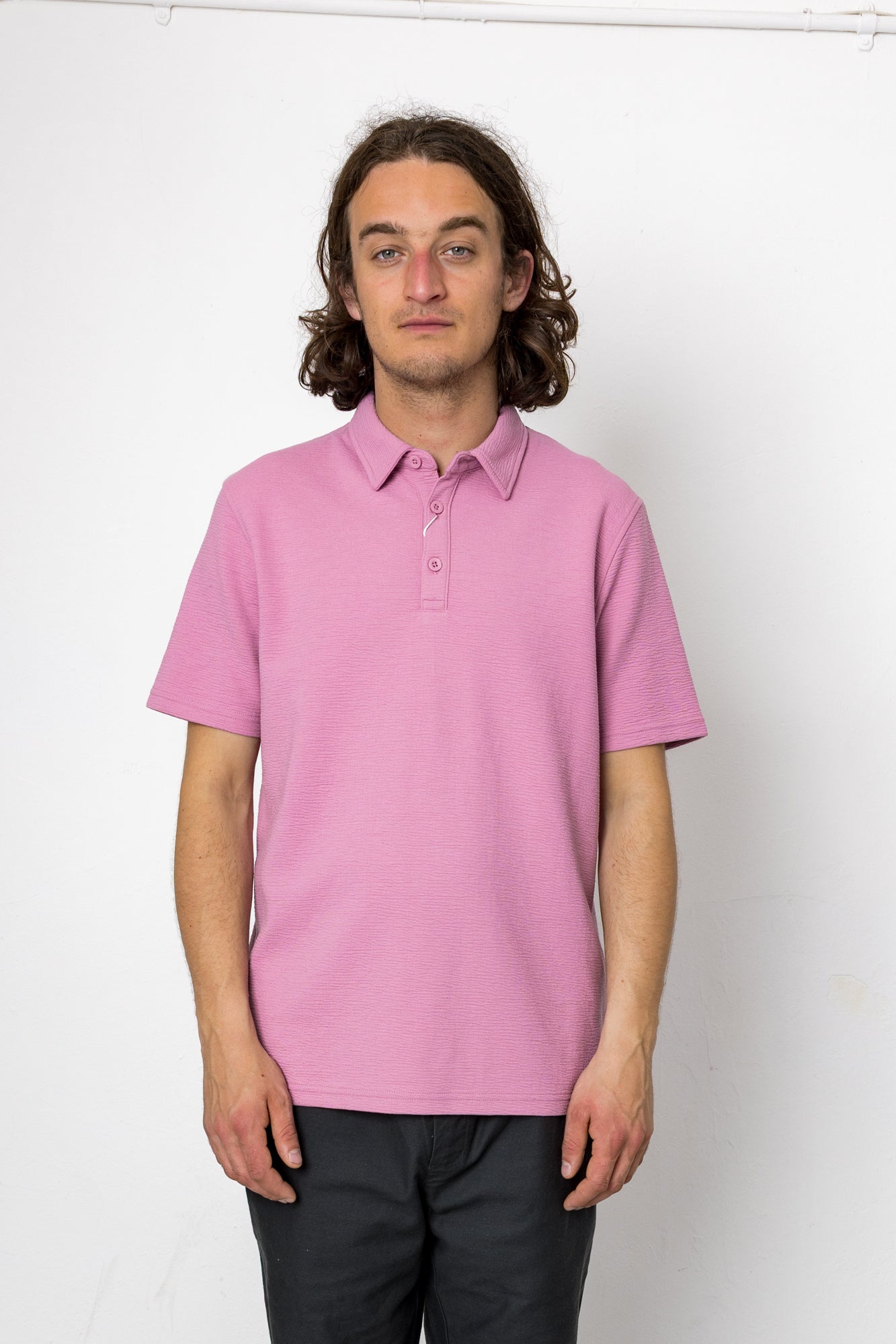 Person wearing a pink polo shirt against a white background