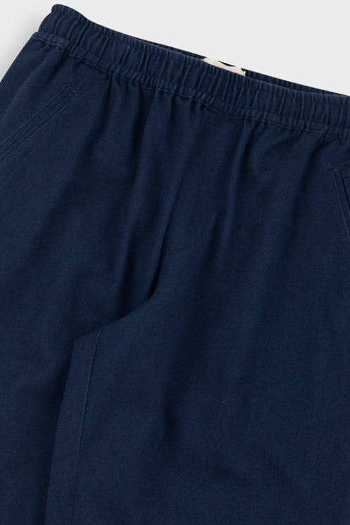 Close-up of dark navy blue pants showing the elastic waistband and side pocket seam.
