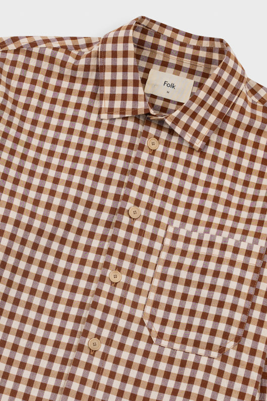 A close-up of a brown and beige gingham checkered button-down shirt by Folk, featuring a classic collar and light-colored buttons.
