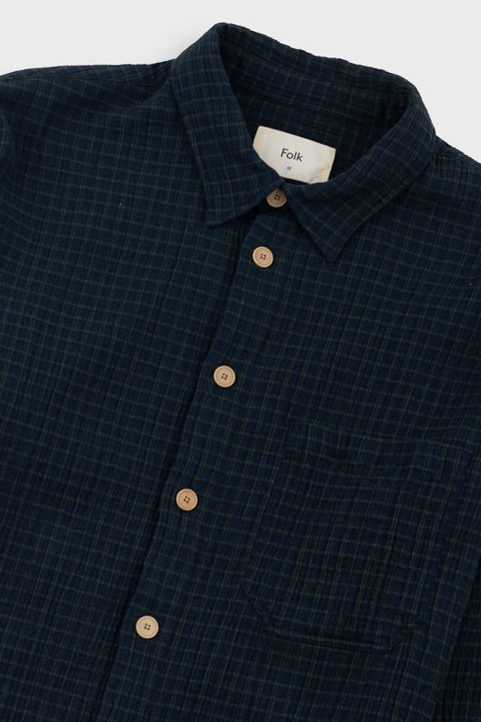 Navy checkered shirt with brown buttons on a white background