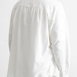 A man viewed from the back wearing a white long-sleeve button-up shirt and dark blue jeans against a plain white background.