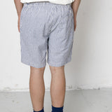 Person wearing blue and white striped shorts with a plain background