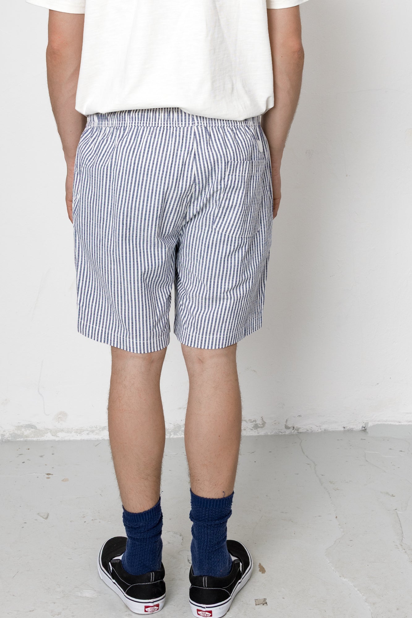 Person wearing blue and white striped shorts with a plain background