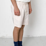 Person wearing white shorts, navy socks, and black shoes on a plain background
