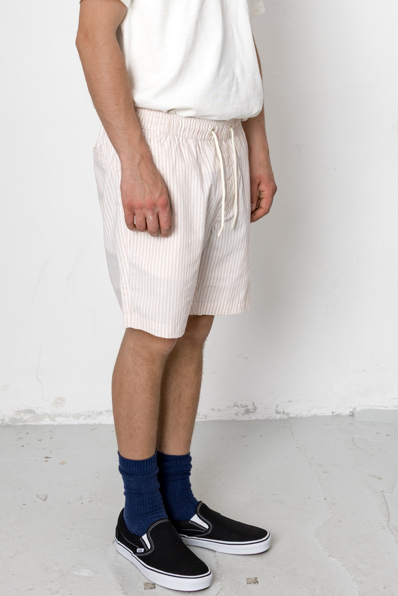 Person wearing white shorts, navy socks, and black shoes on a plain background