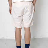 Person wearing white striped shorts and black sneakers on a plain background