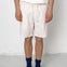 Person wearing white shorts with a subtle pattern, a white shirt, blue socks, and black shoes on a plain background.