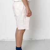 Person wearing white shorts and black sneakers with a white background