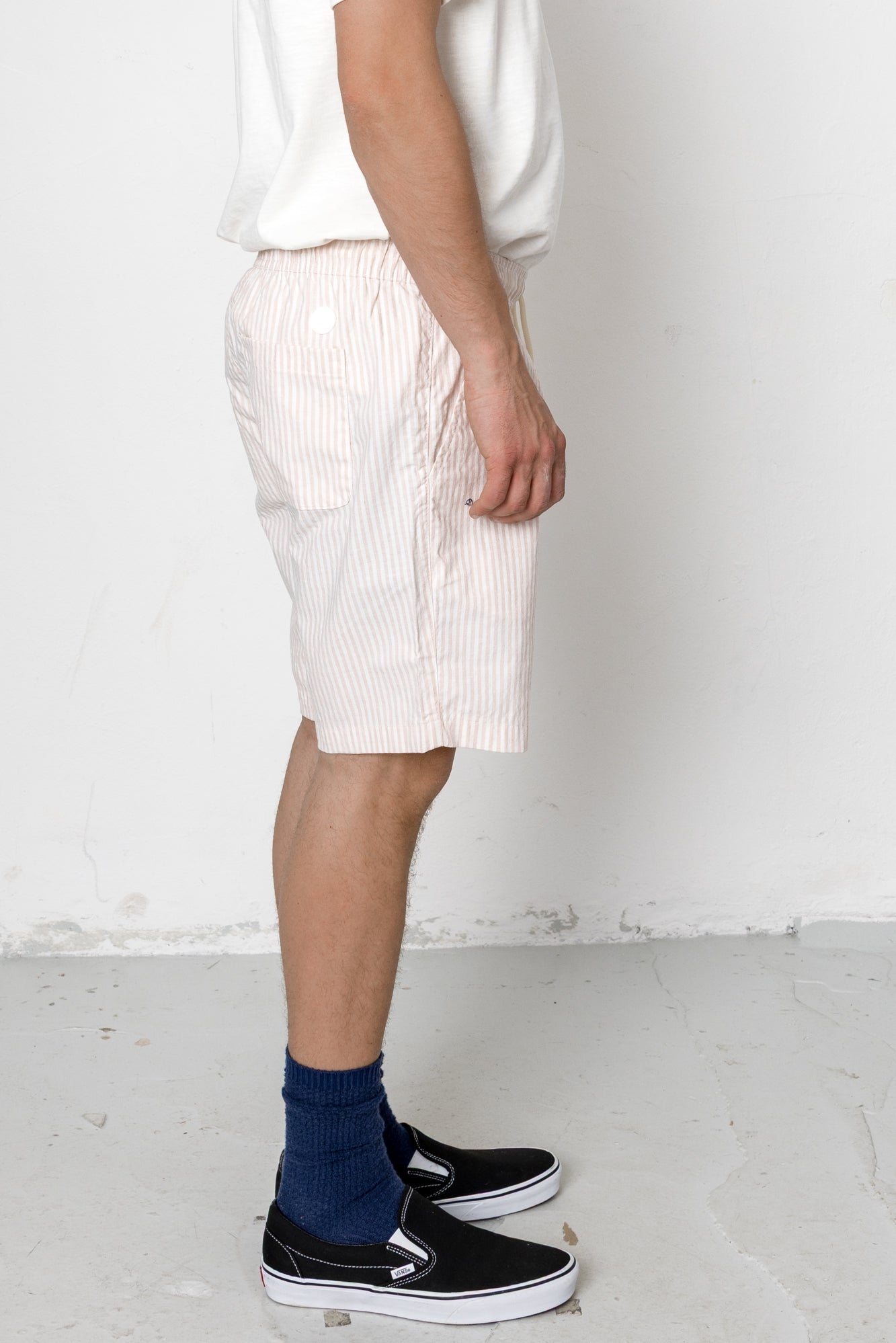 Person wearing white shorts and black sneakers with a white background